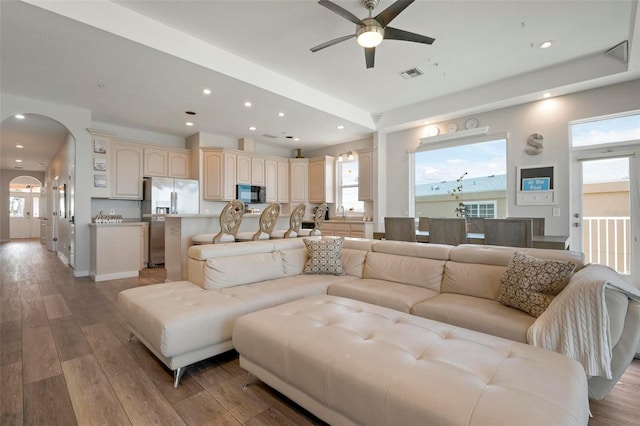 living area featuring plenty of natural light, arched walkways, visible vents, and light wood finished floors