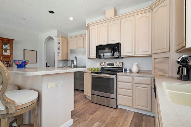 kitchen featuring a breakfast bar area, light wood-type flooring, light countertops, stainless steel appliances, and a sink