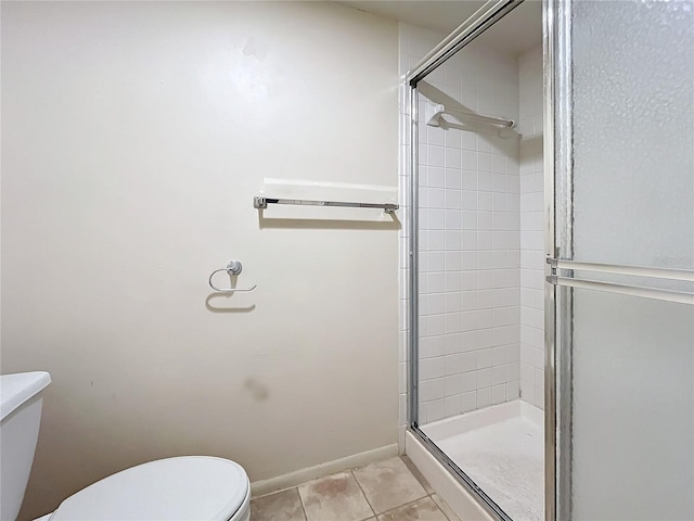 bathroom featuring a shower with door, tile patterned floors, and toilet