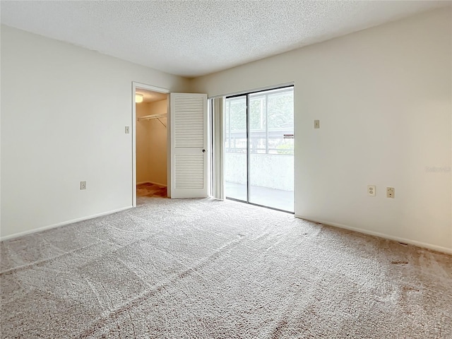 unfurnished bedroom with a textured ceiling, carpet flooring, a walk in closet, and a closet