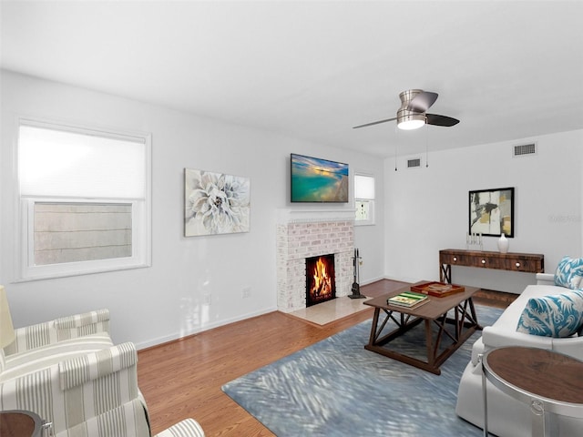 living room with ceiling fan, a fireplace, and wood-type flooring