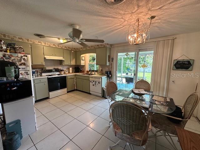 kitchen with hanging light fixtures, light tile patterned floors, ceiling fan with notable chandelier, white appliances, and a textured ceiling