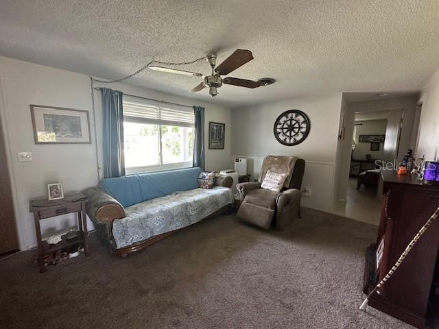 carpeted living room featuring ceiling fan and a textured ceiling