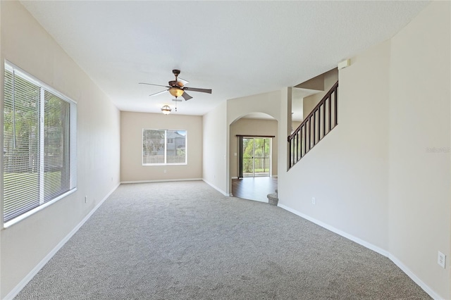 carpeted spare room featuring a wealth of natural light and ceiling fan