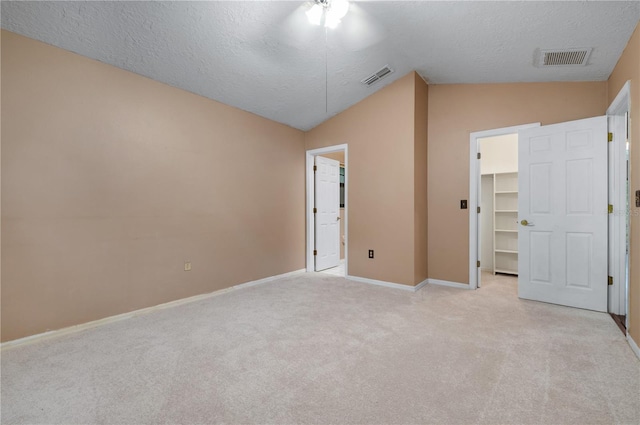 unfurnished bedroom with vaulted ceiling, a spacious closet, light colored carpet, and a closet