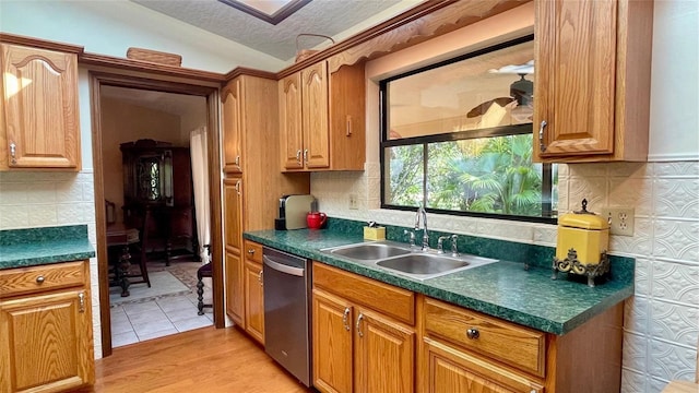 kitchen with sink, dishwasher, light hardwood / wood-style floors, a textured ceiling, and vaulted ceiling