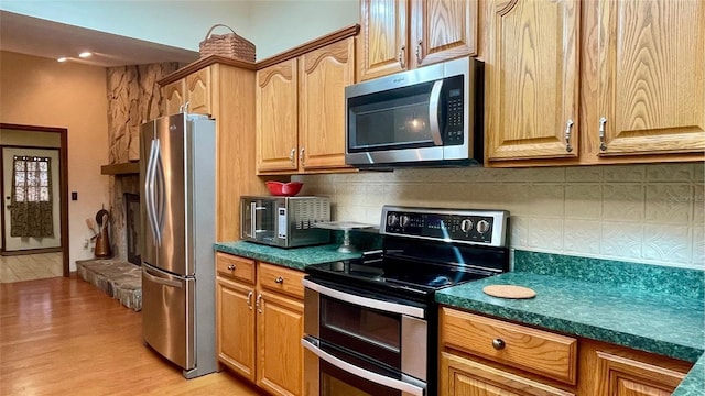 kitchen featuring decorative backsplash, light hardwood / wood-style floors, and appliances with stainless steel finishes