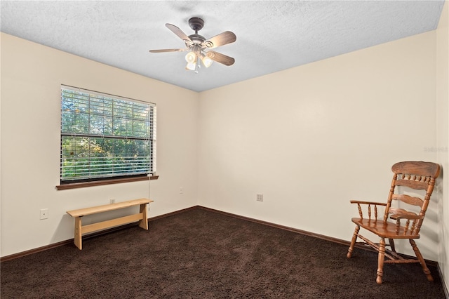 empty room featuring a textured ceiling, baseboards, dark colored carpet, and ceiling fan