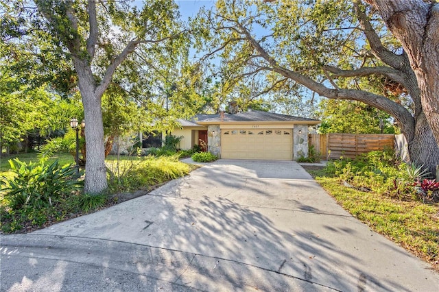 view of front of home with stucco siding, an attached garage, concrete driveway, and fence