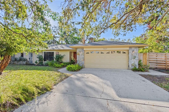 ranch-style home with fence, concrete driveway, stucco siding, stone siding, and an attached garage