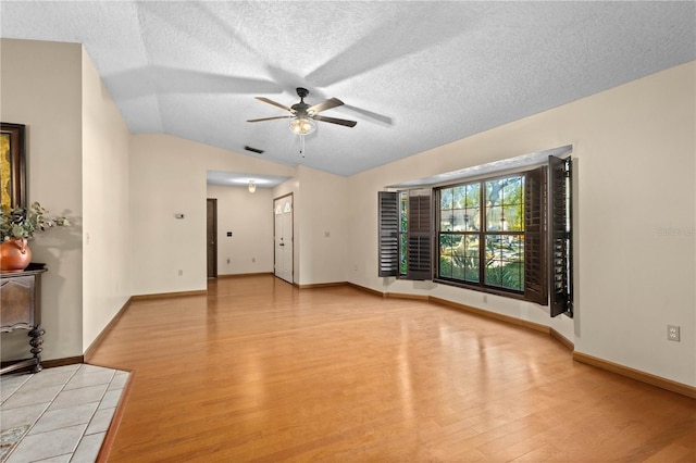 unfurnished room with light wood-type flooring, visible vents, a textured ceiling, ceiling fan, and vaulted ceiling