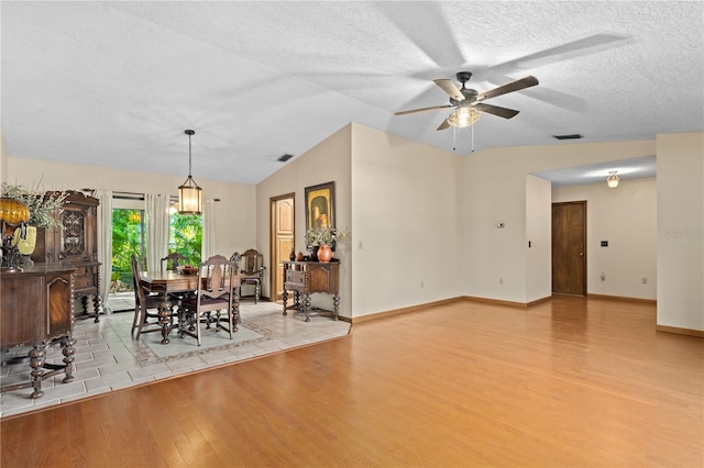 unfurnished dining area featuring visible vents, lofted ceiling, ceiling fan, a textured ceiling, and light wood-type flooring