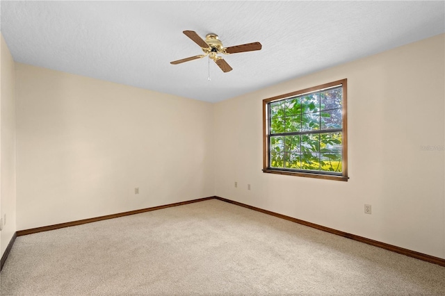 carpeted spare room featuring ceiling fan, a textured ceiling, and baseboards