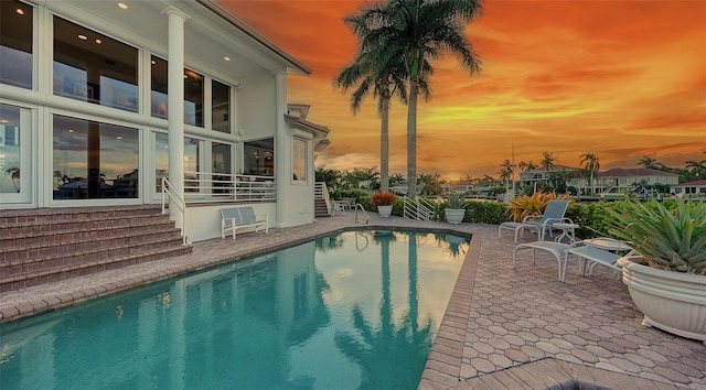 pool at dusk featuring a patio