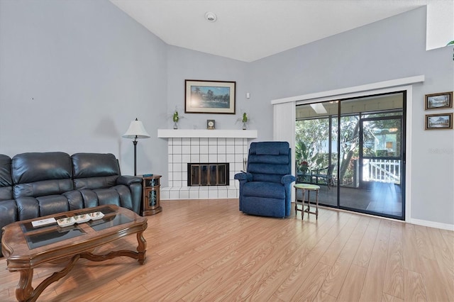 living room with light hardwood / wood-style floors, a fireplace, and vaulted ceiling