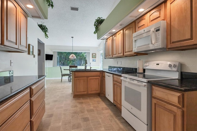 kitchen featuring pendant lighting, a textured ceiling, sink, and white appliances