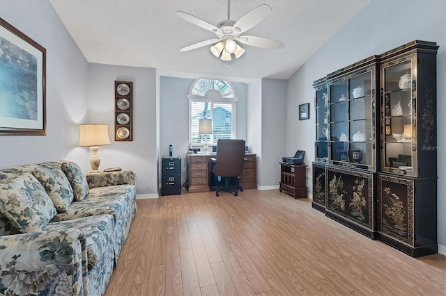 office space featuring ceiling fan, vaulted ceiling, a textured ceiling, and light hardwood / wood-style floors