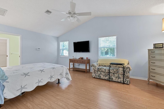 bedroom featuring ceiling fan, vaulted ceiling, a textured ceiling, and light hardwood / wood-style floors