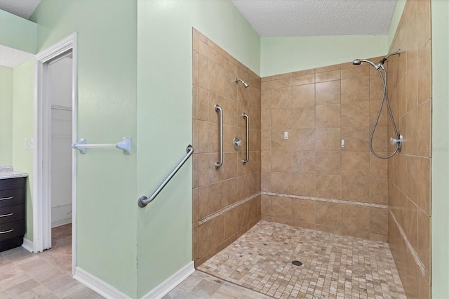 bathroom featuring a textured ceiling, vanity, and tiled shower