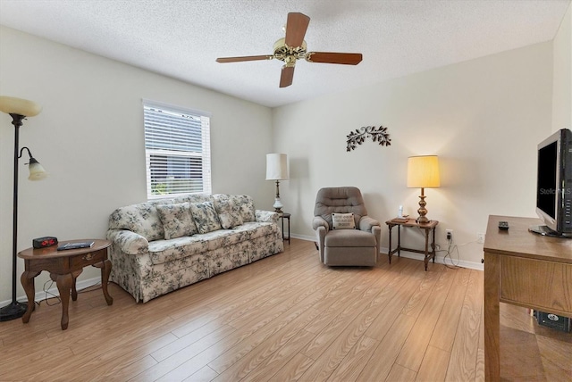 living room featuring ceiling fan, a textured ceiling, and light wood-type flooring