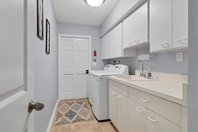 laundry area with washing machine and clothes dryer, a textured ceiling, cabinets, and sink