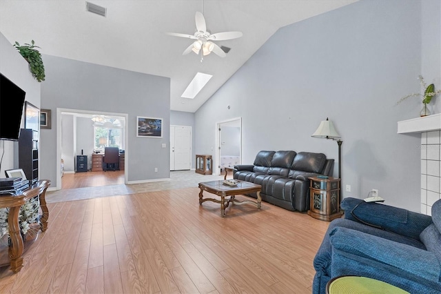 living room with high vaulted ceiling, light wood-type flooring, ceiling fan, and a skylight