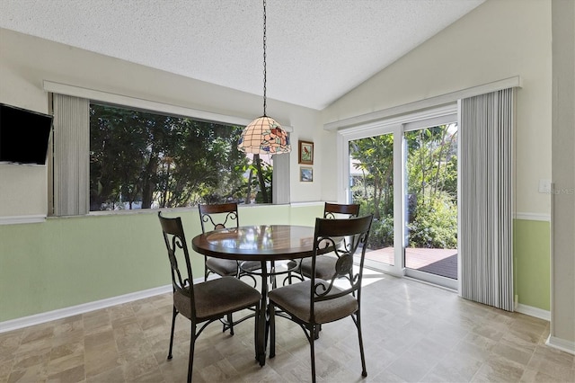 dining room with a textured ceiling and lofted ceiling