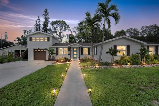 view of front of property with stucco siding, driveway, a garage, and a yard