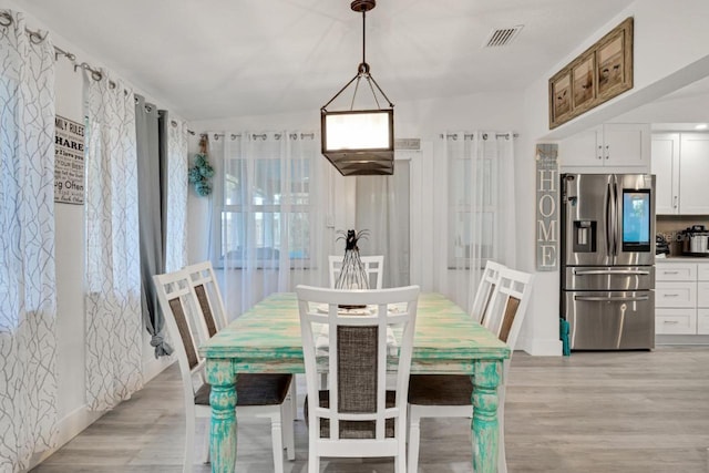 dining space featuring light wood-style floors and visible vents