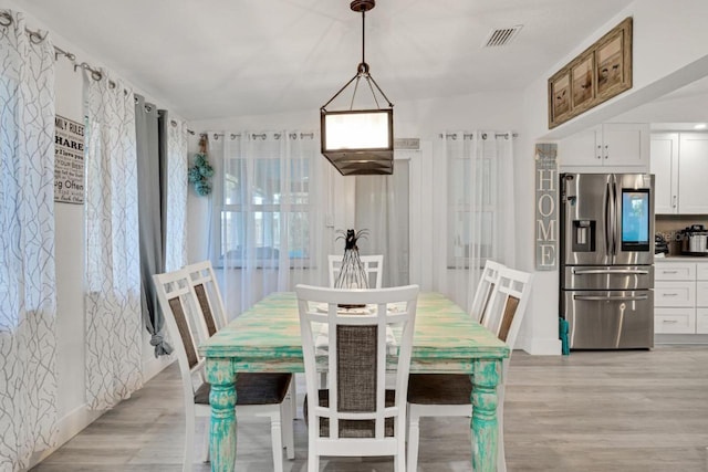 dining space featuring vaulted ceiling and light wood-type flooring