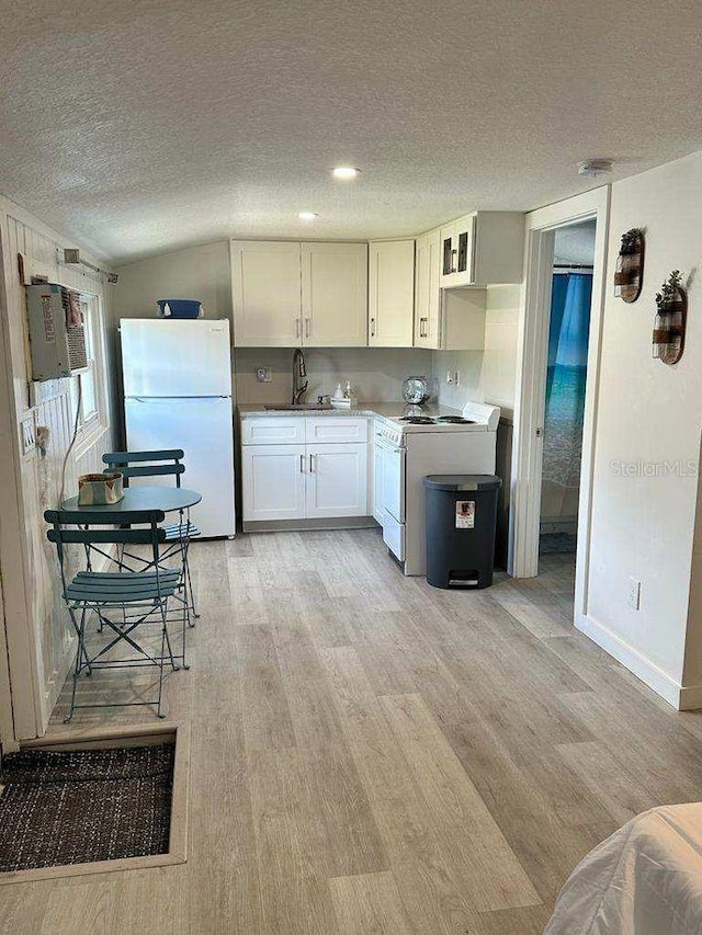 kitchen with a sink, white cabinetry, a textured ceiling, white appliances, and light wood-style floors