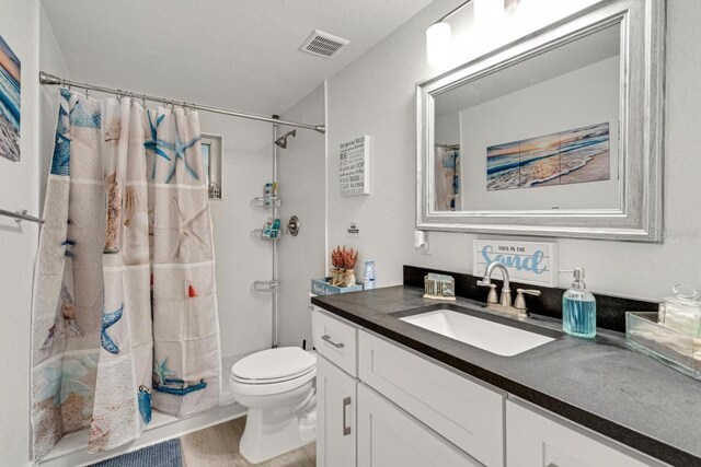full bath with vanity, toilet, visible vents, curtained shower, and wood finished floors