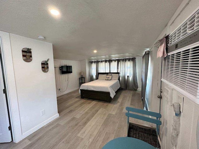 bedroom with baseboards, a textured ceiling, and wood finished floors