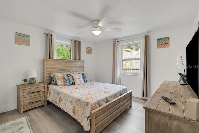 bedroom featuring light hardwood / wood-style flooring, ceiling fan, and multiple windows