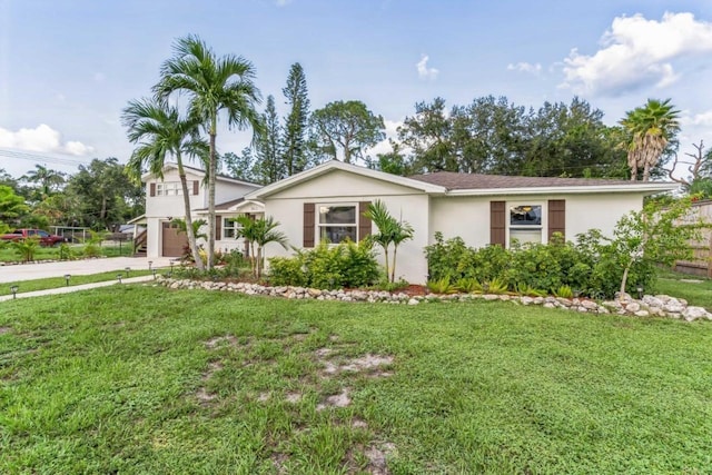 single story home featuring a front yard, concrete driveway, stucco siding, and an attached garage