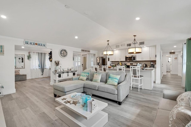 living room with ornamental molding, lofted ceiling, and light hardwood / wood-style flooring