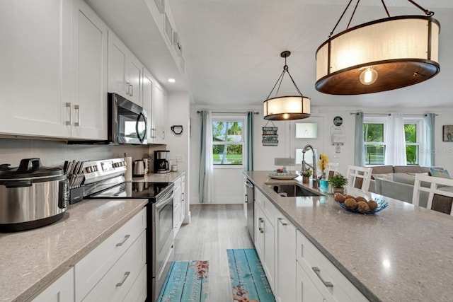 kitchen featuring white cabinetry, light stone counters, sink, hanging light fixtures, and appliances with stainless steel finishes