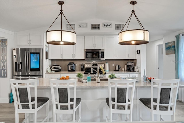 kitchen with an island with sink, decorative light fixtures, appliances with stainless steel finishes, and white cabinetry