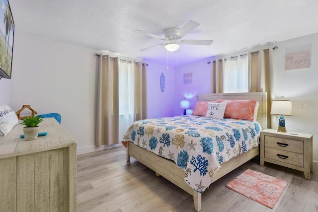 bedroom featuring baseboards, wood finished floors, ceiling fan, and a textured ceiling