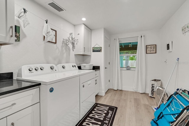 clothes washing area featuring light hardwood / wood-style flooring, cabinets, and washing machine and dryer