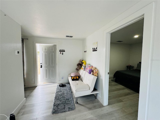 corridor featuring baseboards, light wood-style flooring, and visible vents