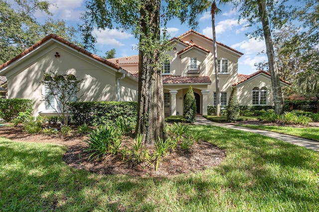 mediterranean / spanish-style home with a balcony and a front lawn