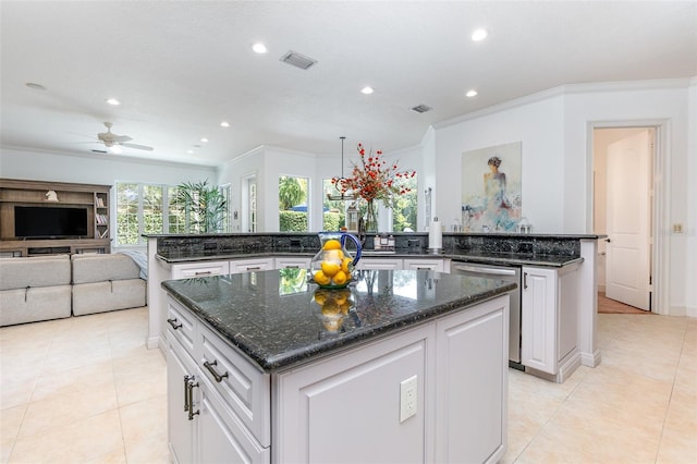 kitchen featuring dark stone counters, white cabinets, ceiling fan, and a kitchen island