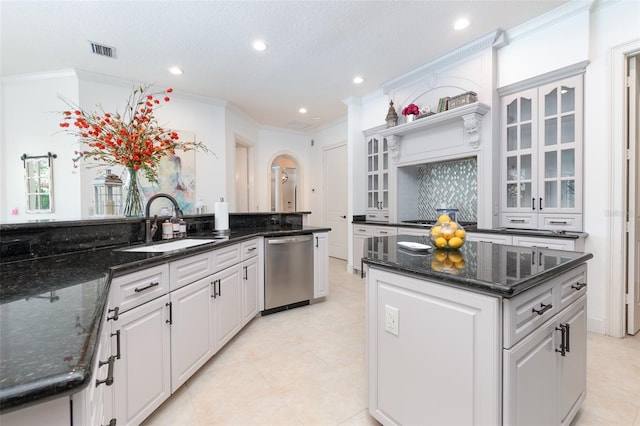 kitchen featuring dark stone countertops, stainless steel dishwasher, white cabinetry, and a kitchen island