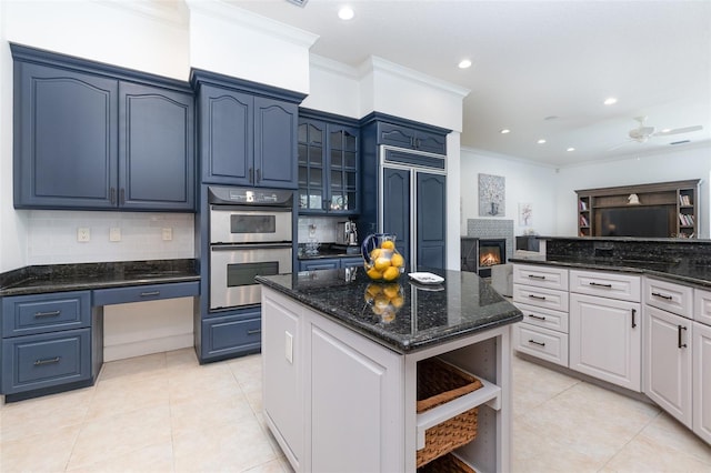 kitchen featuring white cabinets, a kitchen island, stainless steel double oven, ceiling fan, and paneled refrigerator