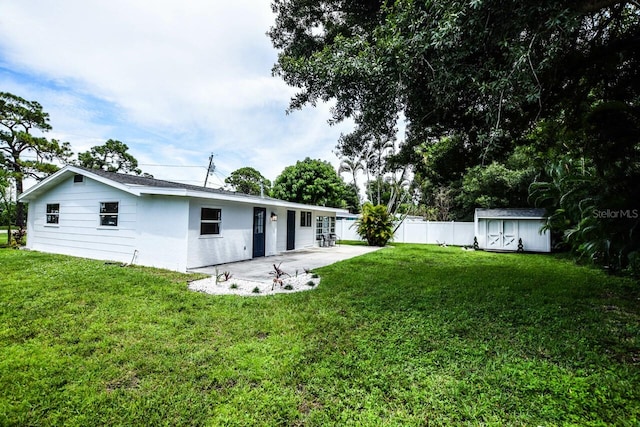 rear view of house featuring a lawn, a storage unit, and a patio area