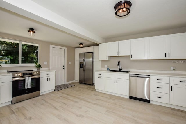 kitchen featuring beam ceiling, white cabinetry, sink, stainless steel appliances, and light wood-type flooring