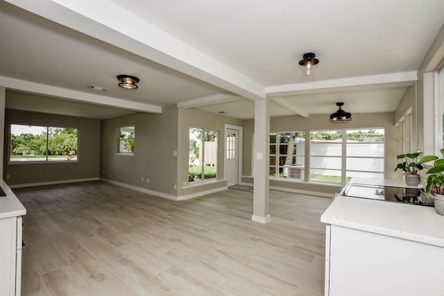 kitchen featuring white cabinets, plenty of natural light, beam ceiling, and light hardwood / wood-style floors