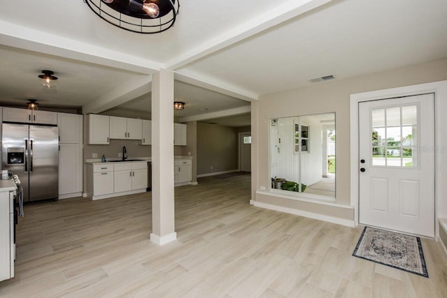 foyer entrance featuring beamed ceiling, light wood-type flooring, and sink