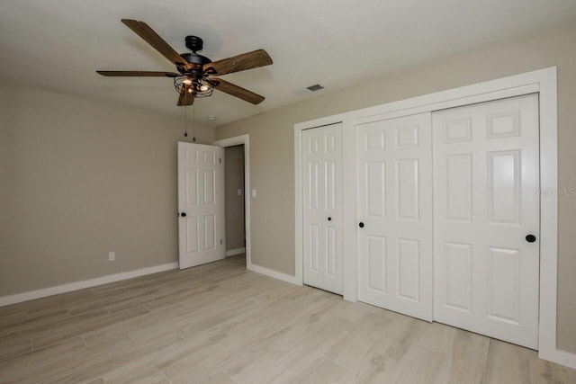 unfurnished bedroom featuring ceiling fan, two closets, and light wood-type flooring